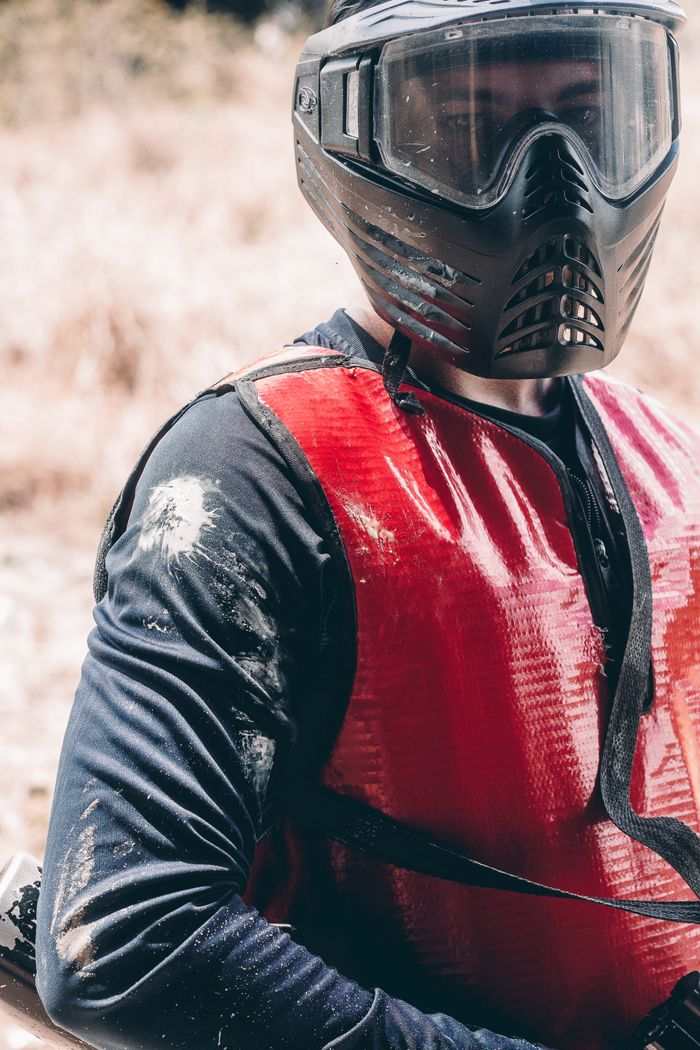 Close-up of a paintball player wearing safety gear and red vest outdoors in Maracanaú, Brazil.