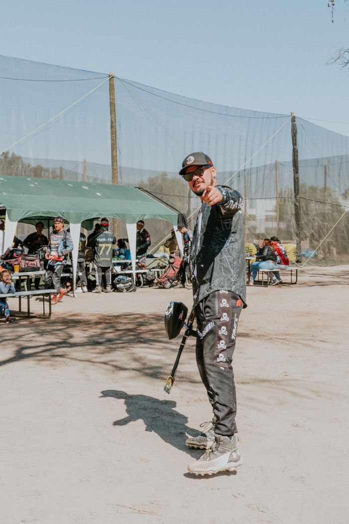services-03 Man in sportswear points enthusiastically on an outdoor paintball field.