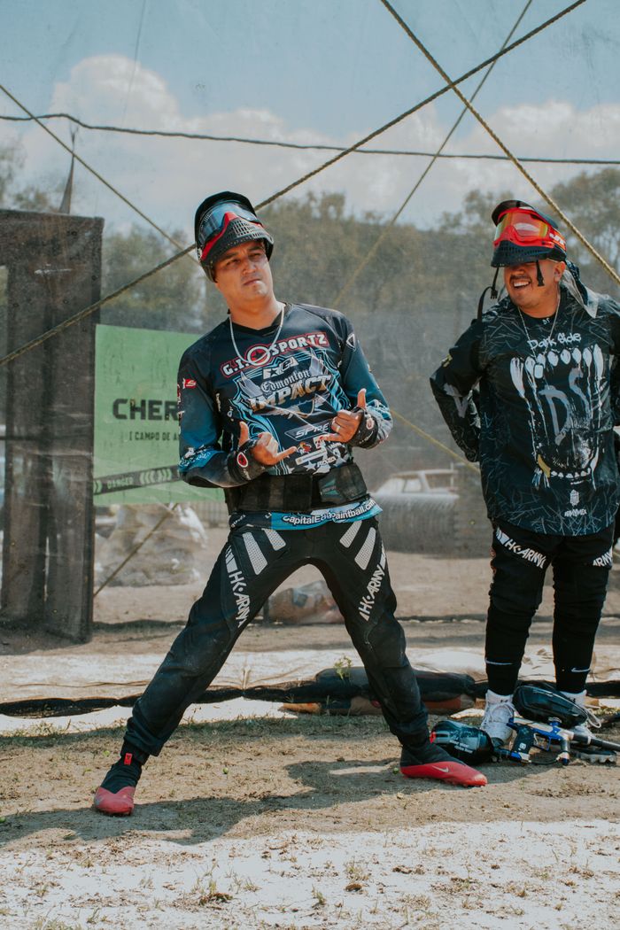 Two men enjoying a vibrant paintball game, wearing protective gear and smiling.